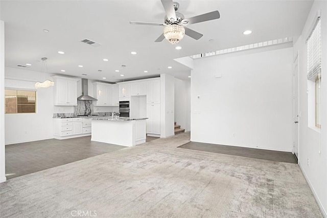 unfurnished living room featuring ceiling fan and carpet flooring