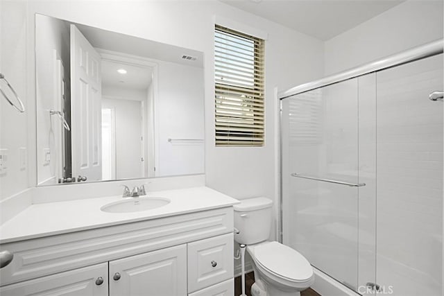 bathroom featuring vanity, toilet, and a shower with shower door