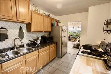 kitchen featuring stainless steel appliances, sink, light tile patterned floors, and backsplash