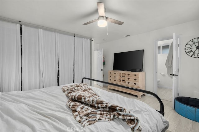 bedroom featuring ceiling fan, ensuite bath, and light hardwood / wood-style floors