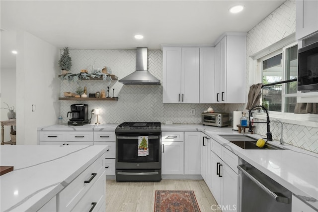 kitchen featuring wall chimney range hood, decorative backsplash, sink, stainless steel appliances, and white cabinets