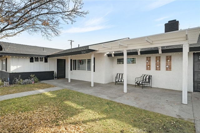 back of property featuring a pergola, a patio area, and a lawn