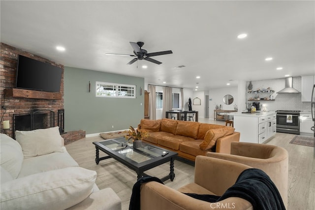 living room featuring ceiling fan, light hardwood / wood-style flooring, and a fireplace