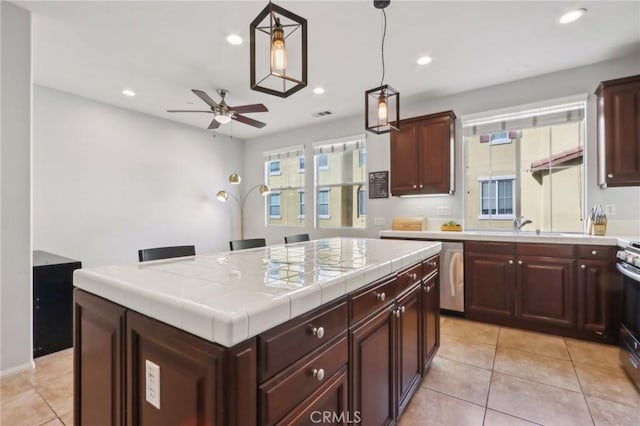 kitchen featuring tile countertops, ceiling fan, a healthy amount of sunlight, decorative light fixtures, and a kitchen island