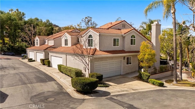 mediterranean / spanish home featuring concrete driveway, a chimney, a tile roof, and stucco siding