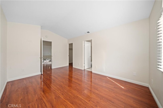 unfurnished room with lofted ceiling, wood finished floors, visible vents, and baseboards