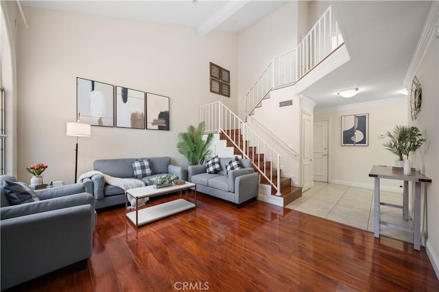 living area with visible vents, stairway, a high ceiling, ornamental molding, and wood finished floors