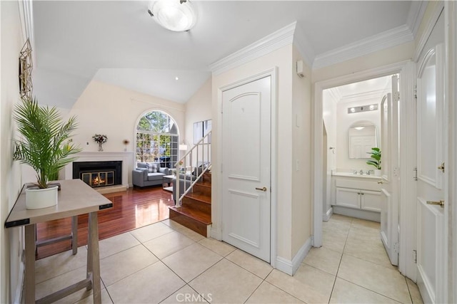 hall with light tile patterned floors, baseboards, lofted ceiling, ornamental molding, and stairs