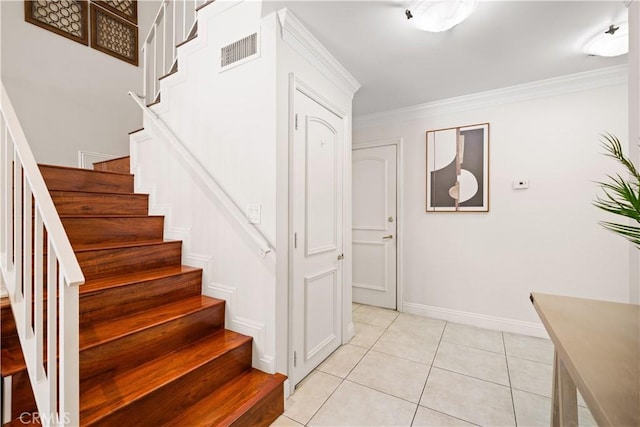 stairway featuring crown molding, baseboards, visible vents, and tile patterned floors