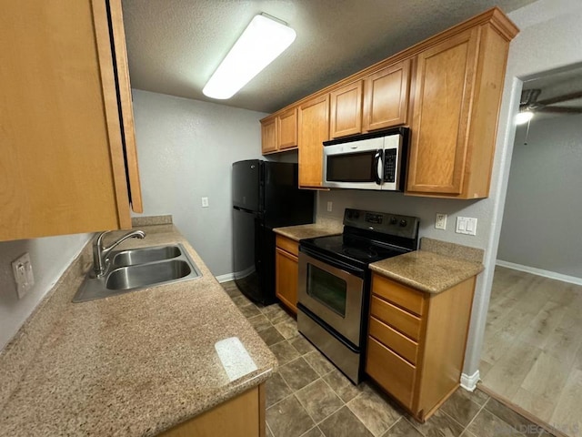 kitchen with ceiling fan, sink, a textured ceiling, and stainless steel appliances