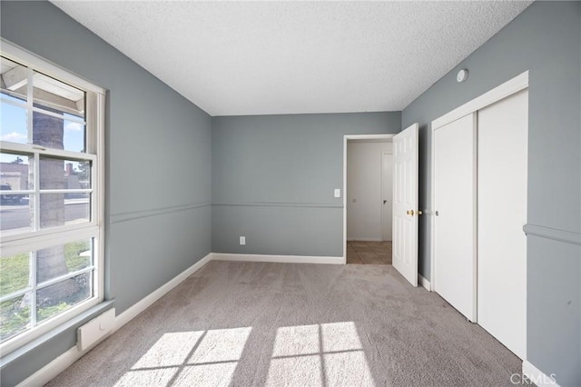 unfurnished bedroom with light colored carpet, a closet, and a textured ceiling