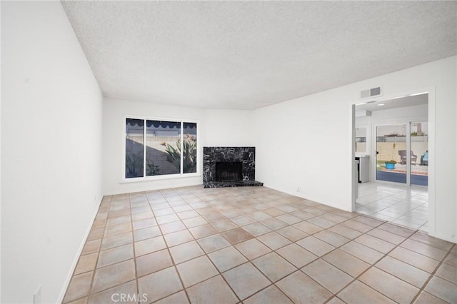 unfurnished living room with a textured ceiling, light tile patterned floors, and a high end fireplace