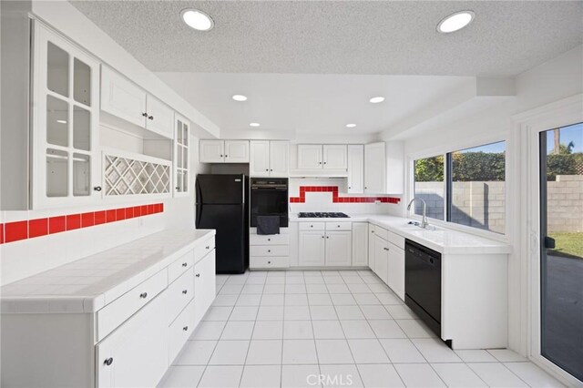 kitchen featuring black appliances, backsplash, tile counters, and white cabinetry