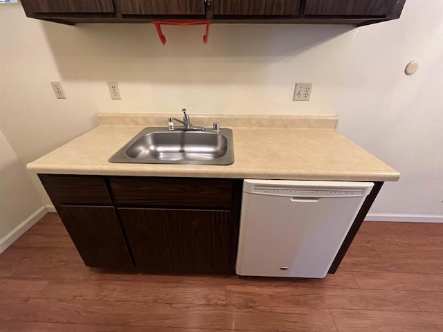 kitchen featuring dark brown cabinets, dark hardwood / wood-style flooring, dishwasher, and sink