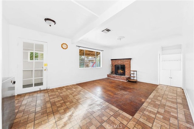 unfurnished living room with a brick fireplace, a wealth of natural light, and beamed ceiling