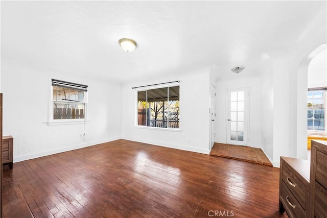 unfurnished living room with plenty of natural light and dark hardwood / wood-style flooring