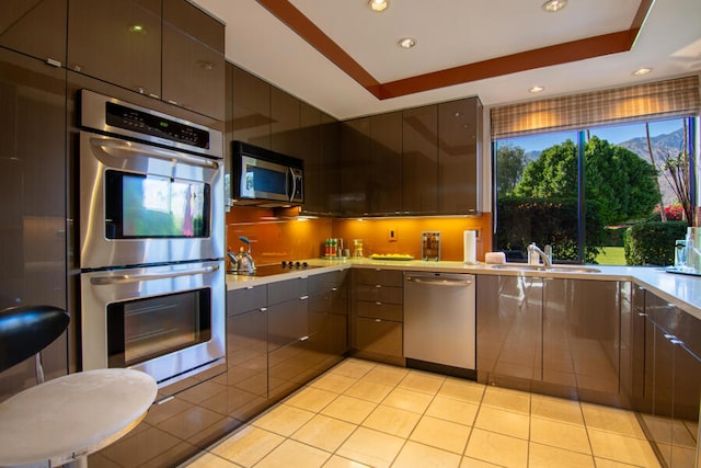 kitchen featuring light tile patterned floors, stainless steel appliances, a raised ceiling, and sink