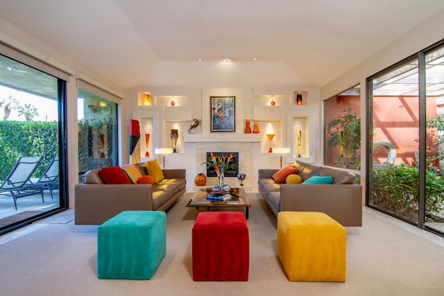 carpeted living room featuring a tiled fireplace and plenty of natural light