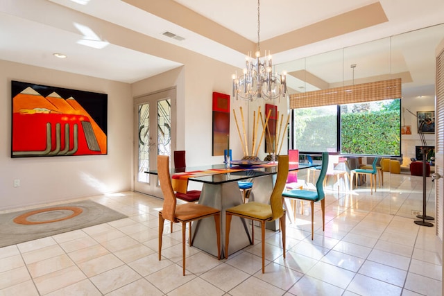 dining room featuring a chandelier, a tray ceiling, french doors, and light tile patterned flooring