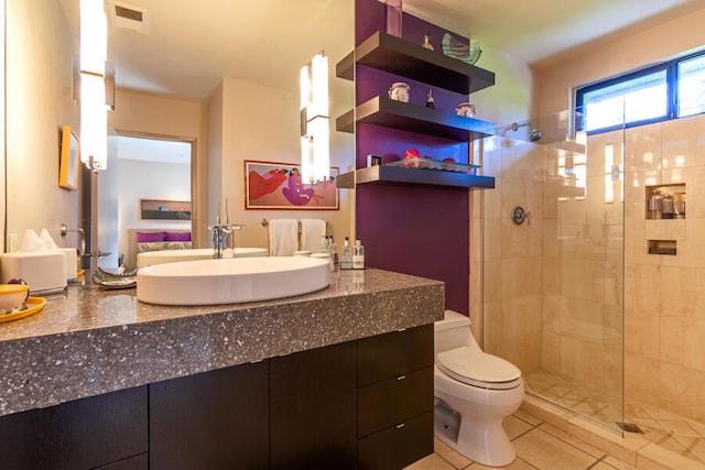 bathroom featuring toilet, tile patterned floors, vanity, and a shower with shower door