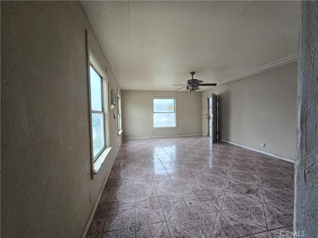 empty room featuring a textured ceiling, ceiling fan, and tile patterned floors