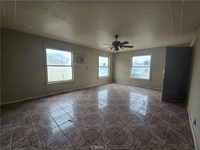 tiled empty room featuring ceiling fan, a textured ceiling, and a wall unit AC