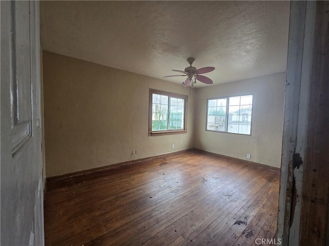 empty room with ceiling fan, dark hardwood / wood-style floors, and a textured ceiling