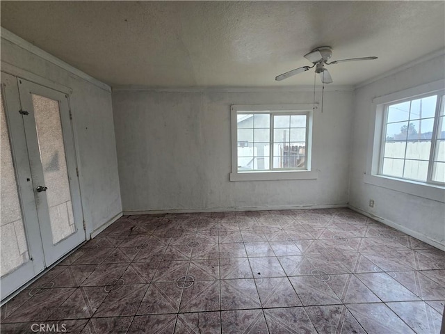 empty room featuring ceiling fan, a textured ceiling, crown molding, and french doors