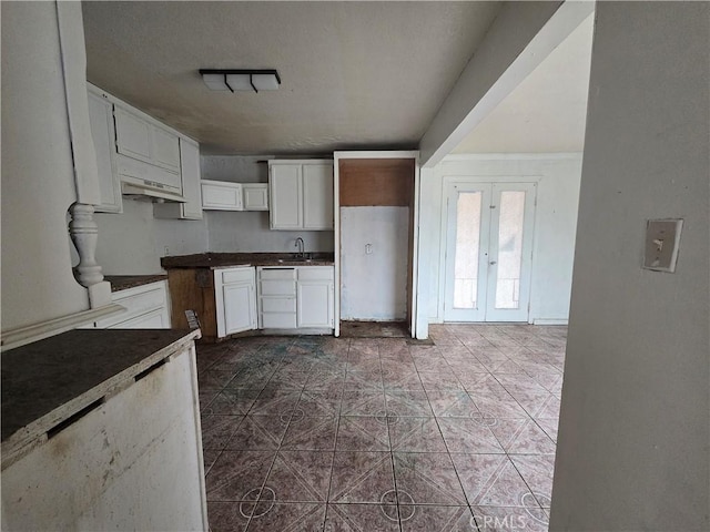 kitchen featuring sink, white cabinetry, dark tile patterned floors, a textured ceiling, and french doors