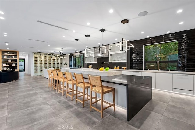 kitchen with decorative light fixtures, white cabinets, a breakfast bar, and a spacious island