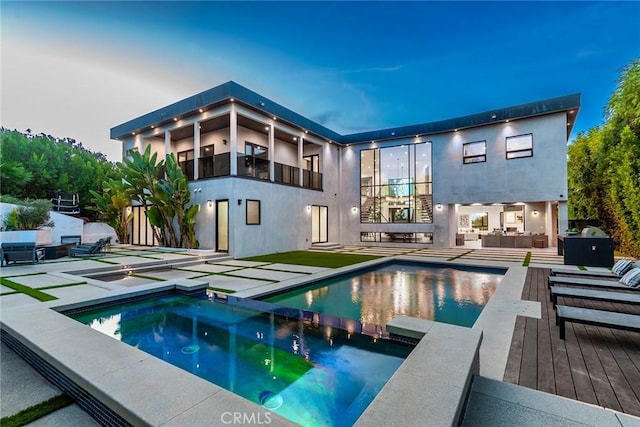 back house at dusk featuring a swimming pool with hot tub, a patio area, and an outdoor hangout area