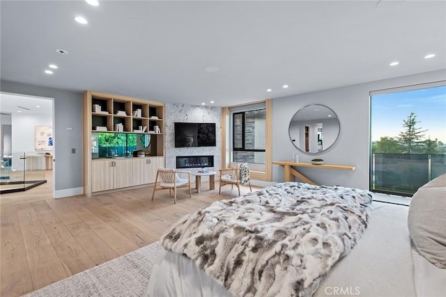 bedroom with access to outside, a premium fireplace, and light wood-type flooring