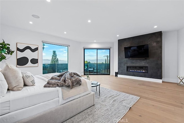 bedroom with light wood-type flooring and a large fireplace