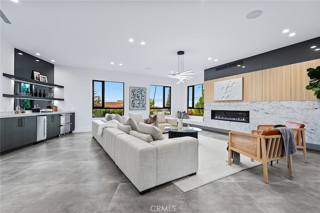 living room featuring bar, a premium fireplace, and an inviting chandelier