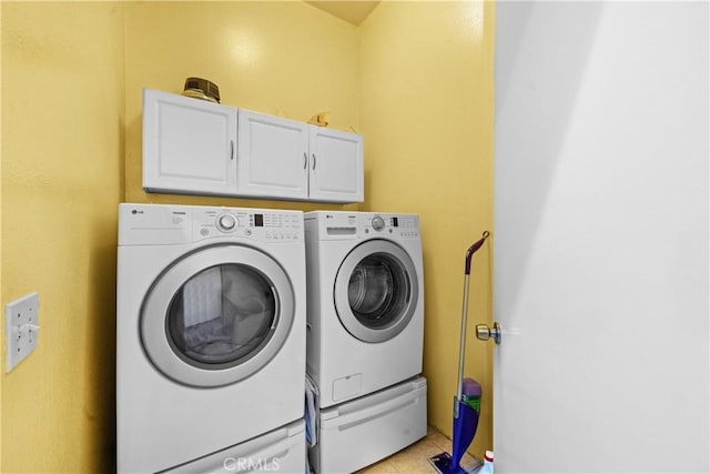 clothes washing area featuring washing machine and dryer, light tile patterned flooring, and cabinets