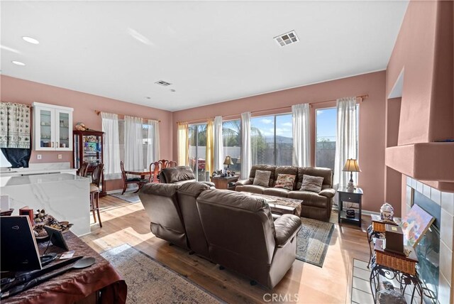 living room with a tiled fireplace and light hardwood / wood-style floors