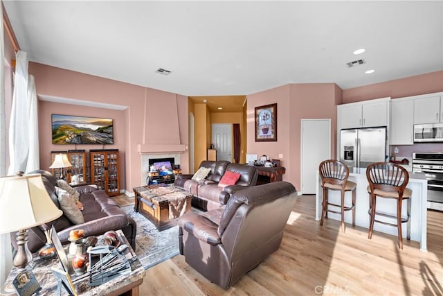 living room with a large fireplace and light hardwood / wood-style flooring