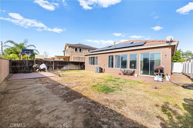 rear view of house featuring a yard, cooling unit, solar panels, and a patio