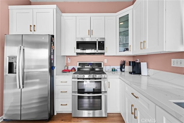 kitchen featuring light stone countertops, white cabinetry, and appliances with stainless steel finishes