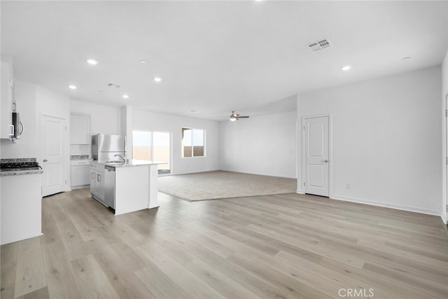 unfurnished living room with ceiling fan and light wood-type flooring