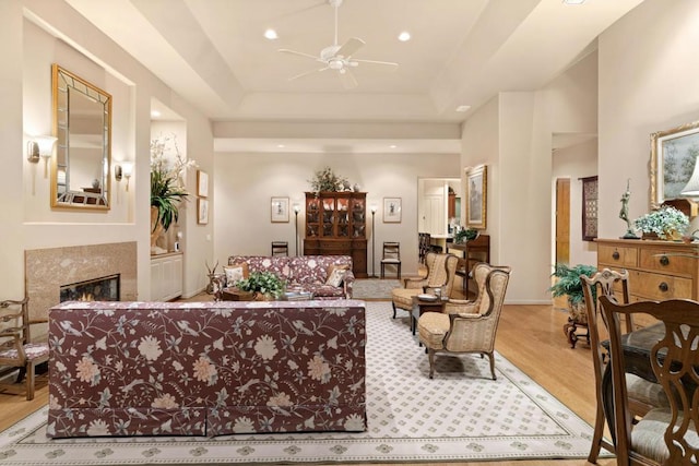 living room featuring light wood-type flooring, ceiling fan, and a tray ceiling