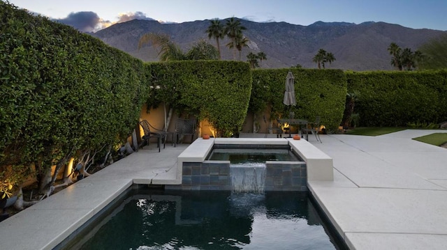 view of swimming pool with a patio area, a mountain view, and an in ground hot tub