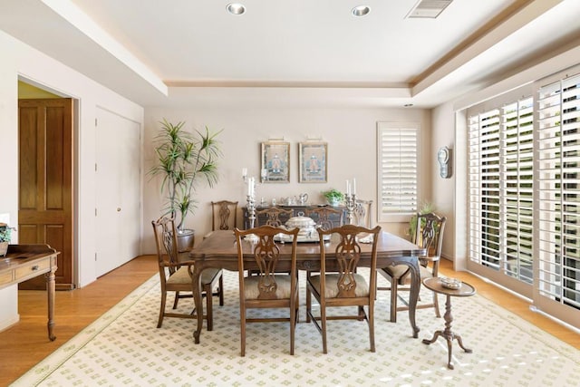 dining area with a tray ceiling and light hardwood / wood-style flooring