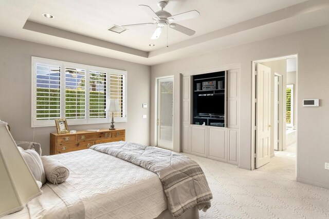 carpeted bedroom featuring ceiling fan and a tray ceiling