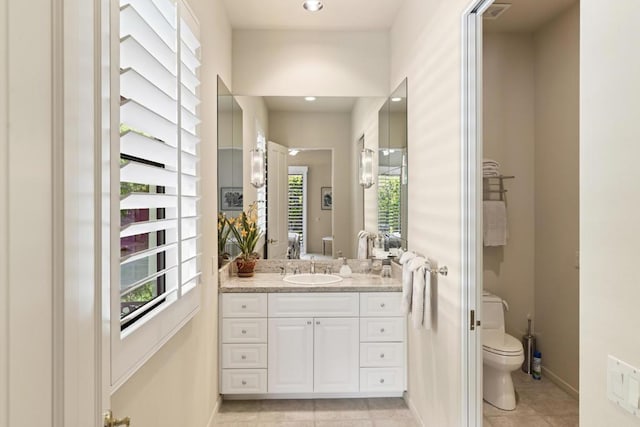 bathroom with plenty of natural light, toilet, vanity, and tile patterned flooring