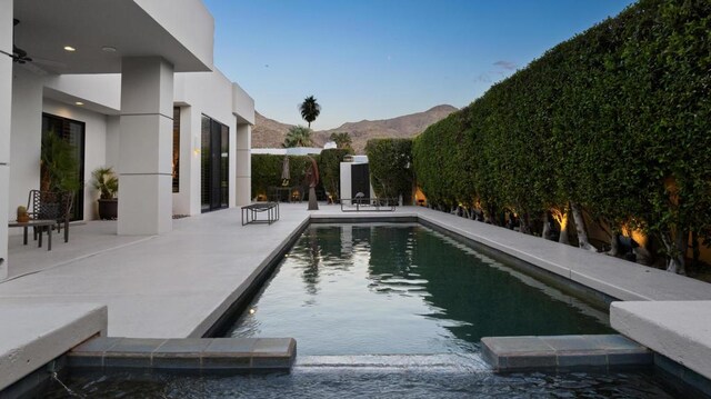 view of swimming pool with ceiling fan, a patio area, and a mountain view