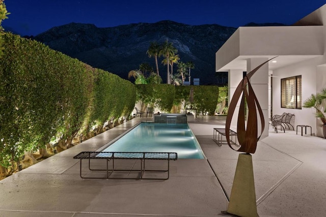 pool at night with a mountain view and a patio