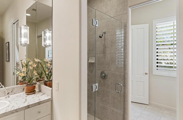 bathroom featuring tile patterned floors, an enclosed shower, and vanity