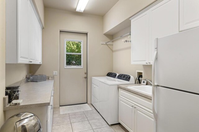 clothes washing area featuring light tile patterned flooring, cabinets, washer and dryer, and sink