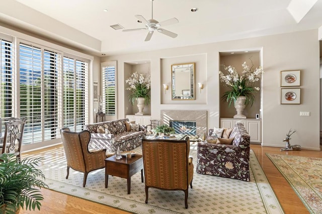 living area with ceiling fan, a fireplace, and light hardwood / wood-style flooring